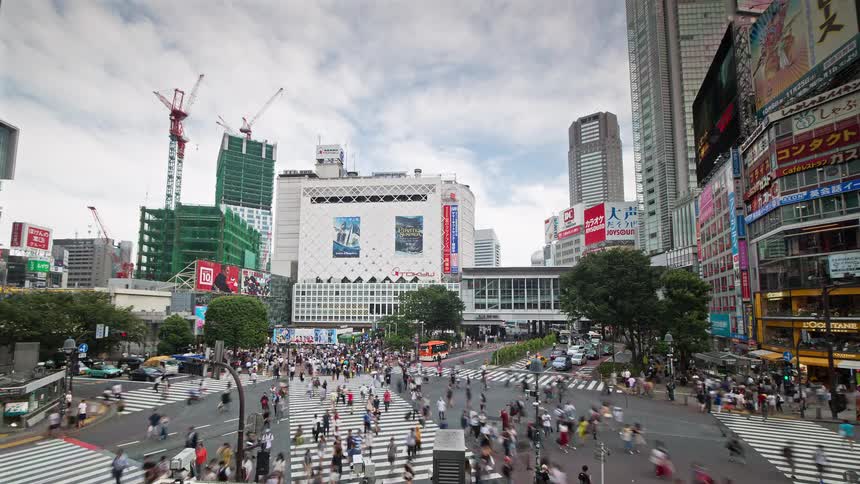 Many pedestrians cross a city intersection after the vehicular traffic moves through on a cloudy day