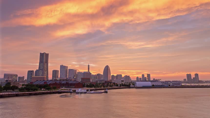 Ships move into a harbor in a metropolis at sunset