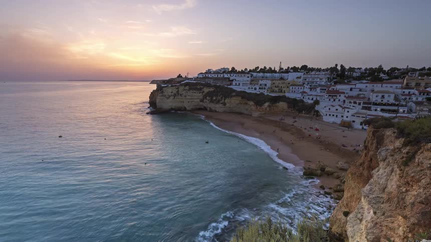 Cliffs with white houses above a beach and calm sea at nightfall