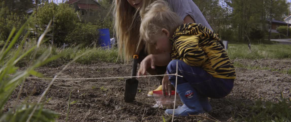 Candid moment of a family planting seeds in a beautiful green meadow together.