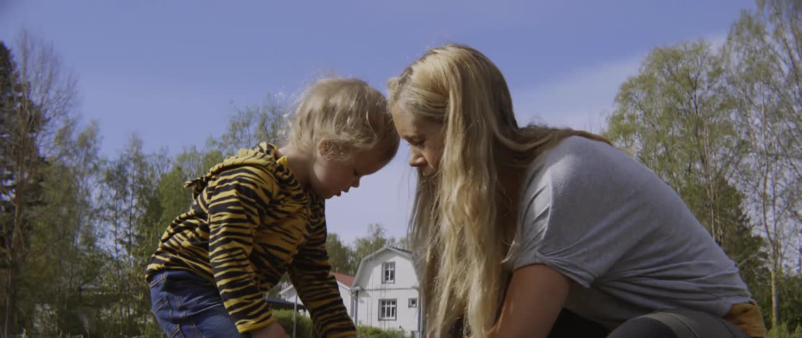 Close up of a woman teaching a young child how to garden in nature.