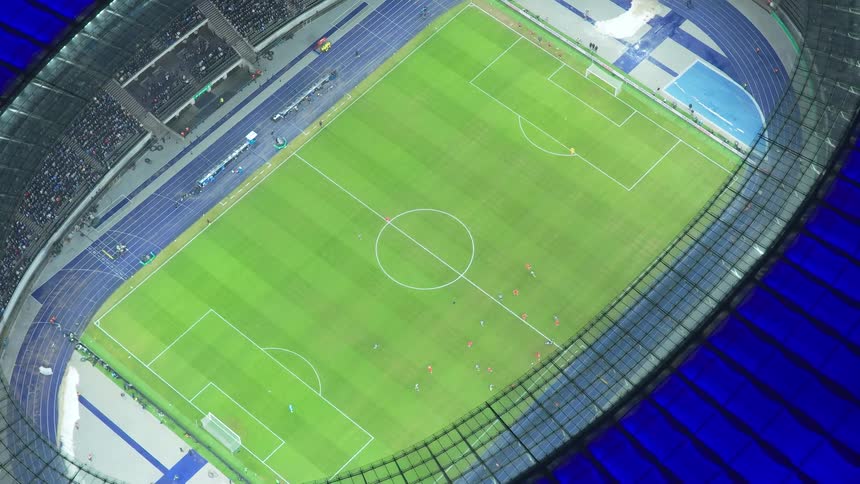 Tilted aerial view of a stadium with a soccer field and players during a match