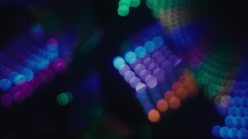 A blurred pattern of vibrant blue purple and green lights with soft bokeh effect