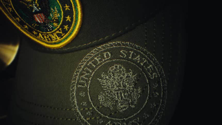 A green baseball hat with a united states army badge and veteran written on the front