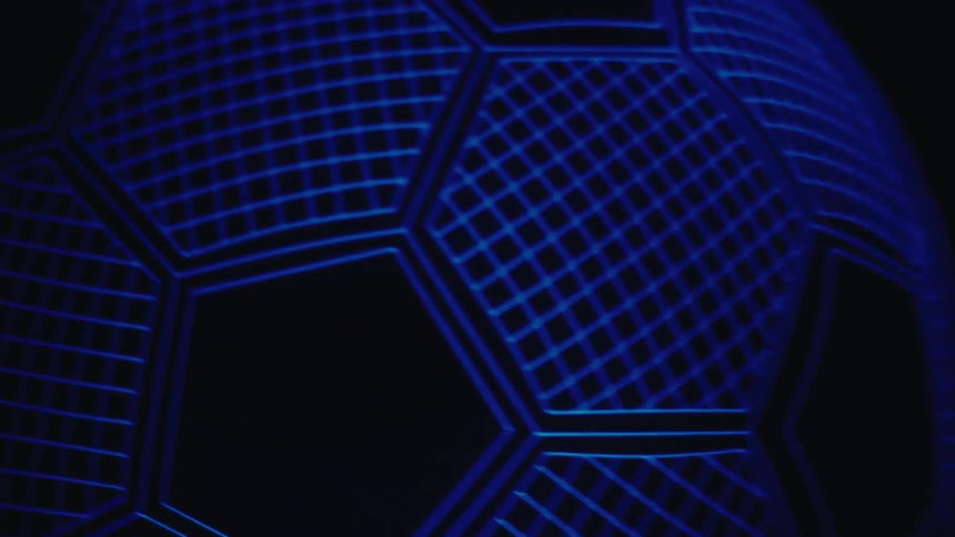 Soccer ball with hexagonal pattern illuminated by blue light in a dark environment