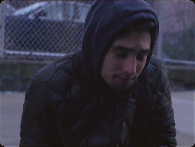 Person sitting holding wrist with a small bleeding cut next to a skateboard