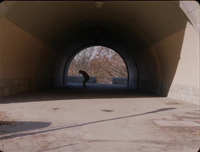 Man skateboarding through a tunnel and performing tricks