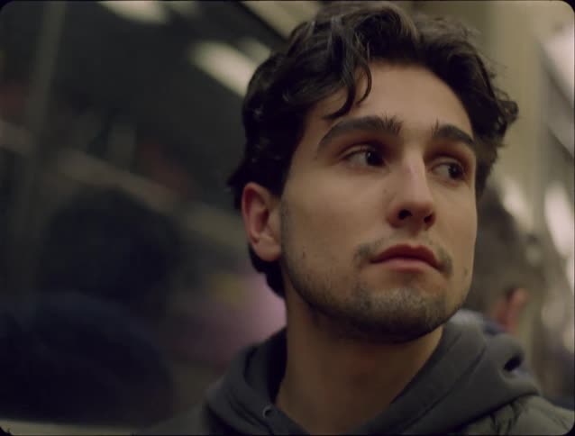 Young man looking to the side inside a subway train