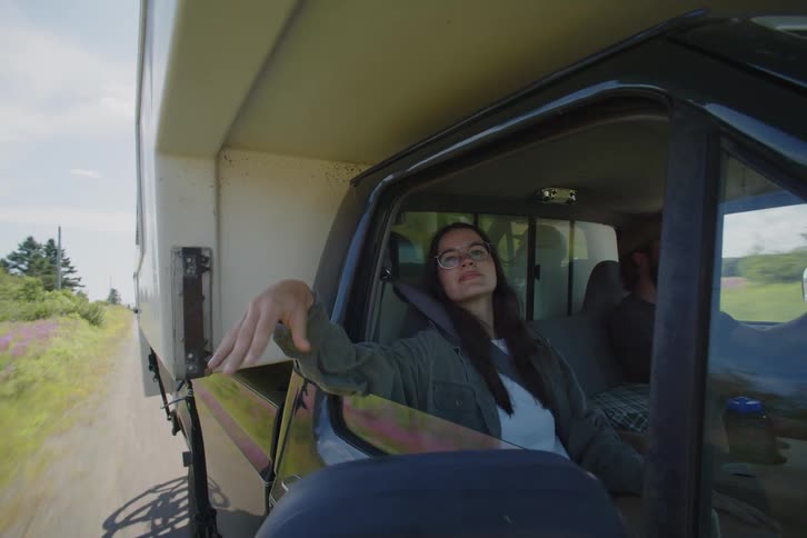 A man and woman driving in a truck with a camper above it