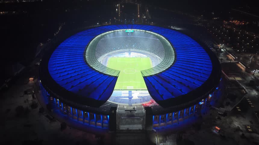 Aerial view of a soccer stadium with players on the field and people in the stands