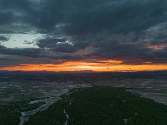 Orange clouds at sunset over vegetation and flooded terrain