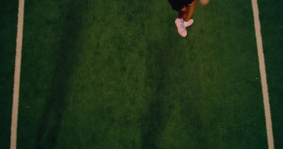Player kicking a soccer ball on a field seen from above