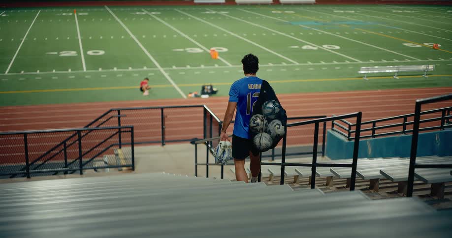 A man with soccer balls walking into a stadium