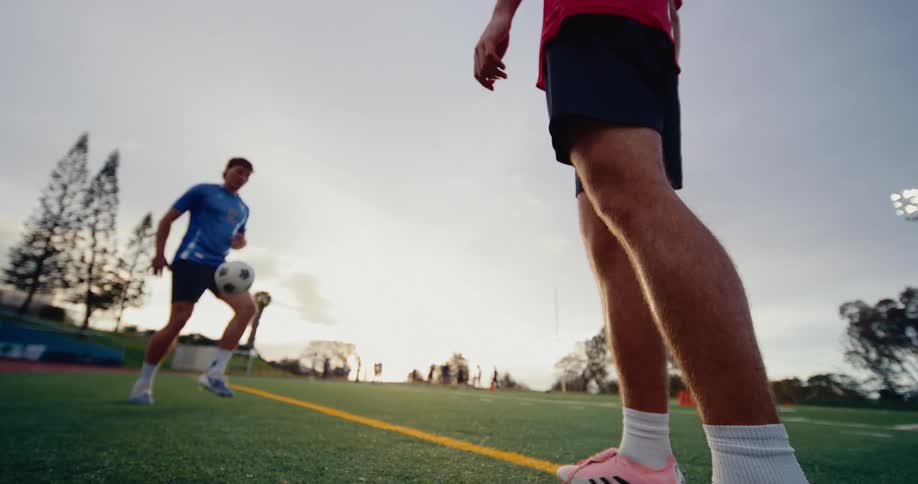 Two soccer players stand on the field kicking the ball back and forth to each other