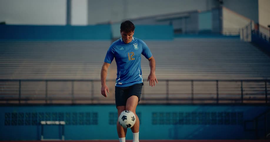 Male soccer player drills by kicking a ball at a sports venue