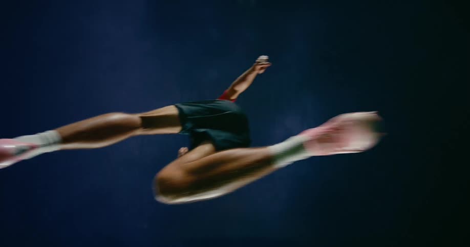 A barefoot soccer player leaps into the night
