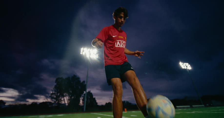 The man is kicking the soccer ball on the field