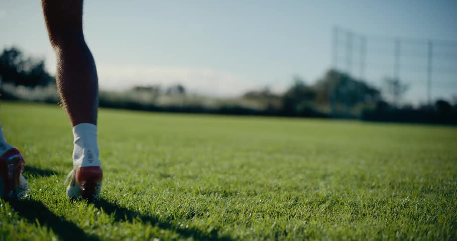 Male soccer player dribbles the soccer ball while another athlete stands nearby on a summer day