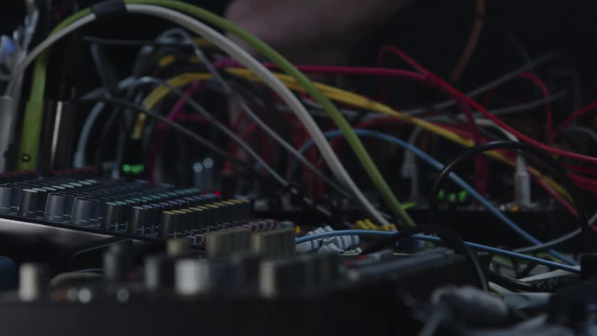 Mans hands moving dials and cables on an electronic soundboard