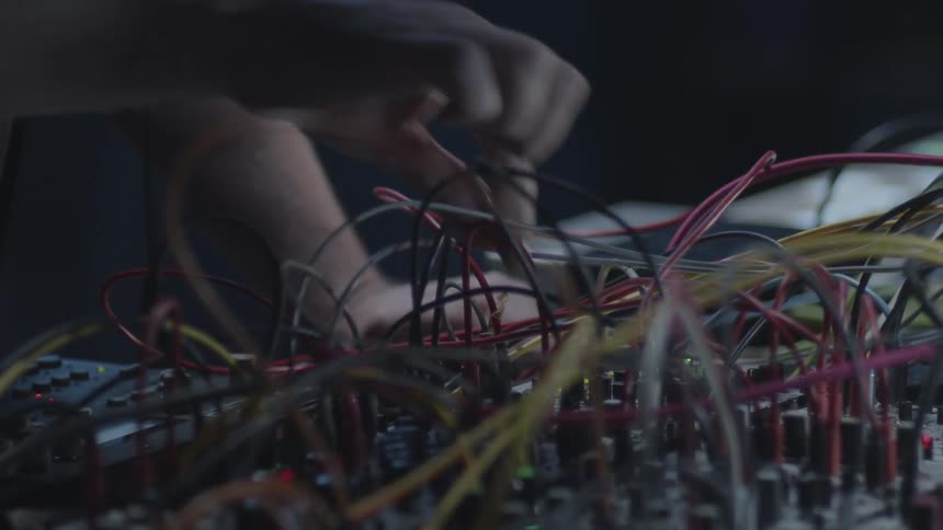 Mans hands moving wires and cables on an electronic soundboard