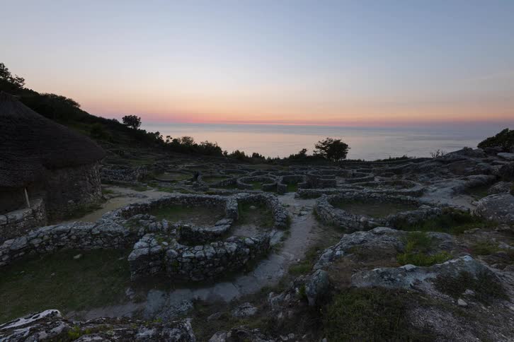 Road and stone walls on a mountain on the coast overlooking the water as the sun sets on the horizon
