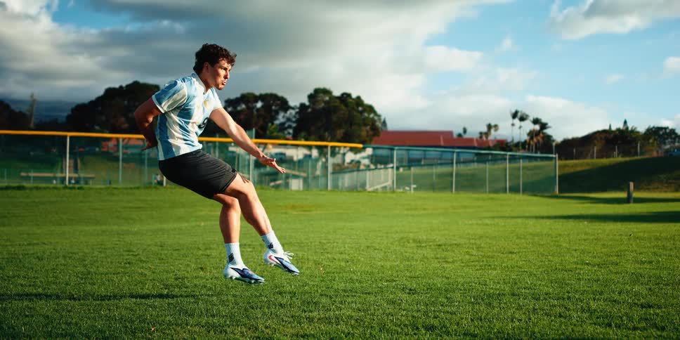 A man kicks a soccer ball across a grass field