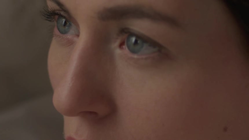 A woman stares straight ahead before looking down