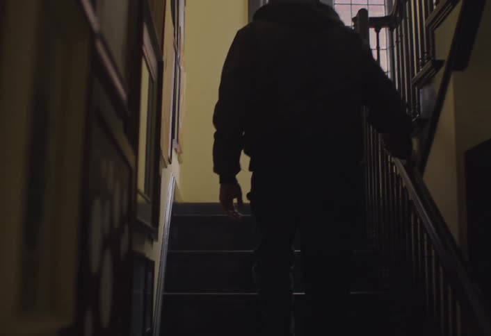 Man walks up an indoor staircase holding the handrail