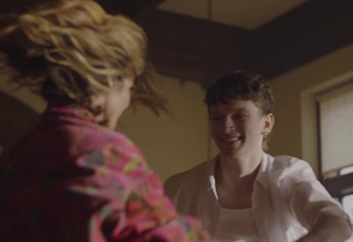 A man and woman hold hands and dance together in an indoor living space