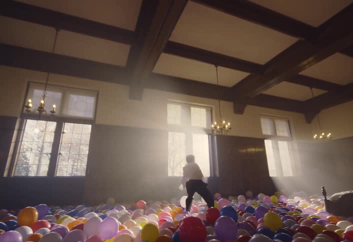 A young man performs a modern dance in a room filled with balloons