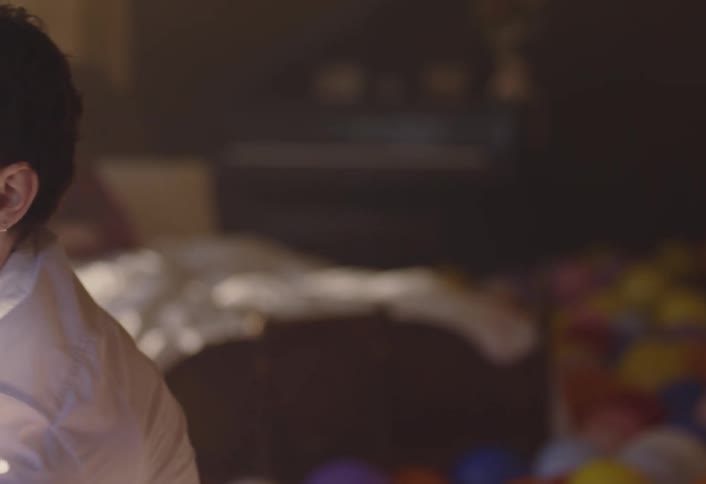 A young man performs an unusual dance in a room filled with balloons