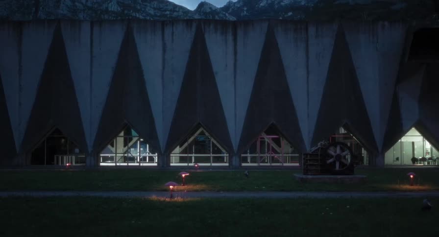 Woman walks through a building located near the mountains at night