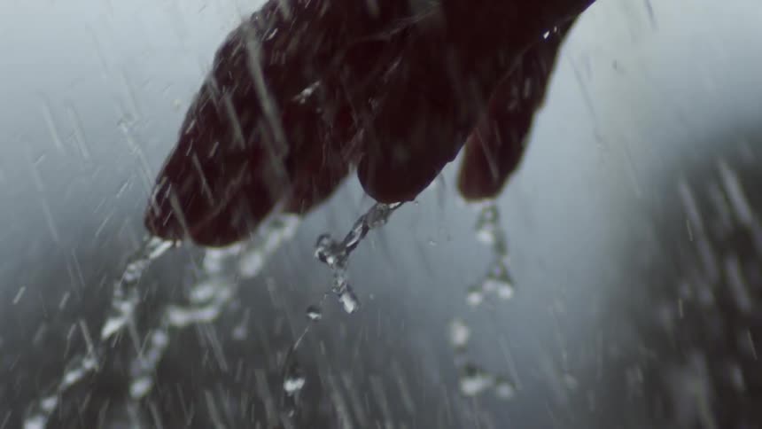 The rain is pouring down hard on a person's hand