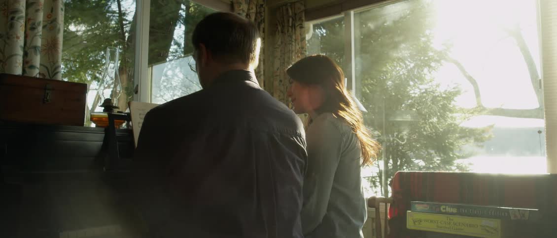 A man and woman sit at a piano together talking