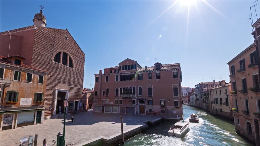 Historic buildings line a canal in a european city under a blue sky
