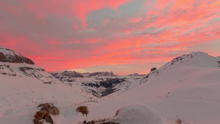 A pink sky at sunset over a snowcovered mountain range