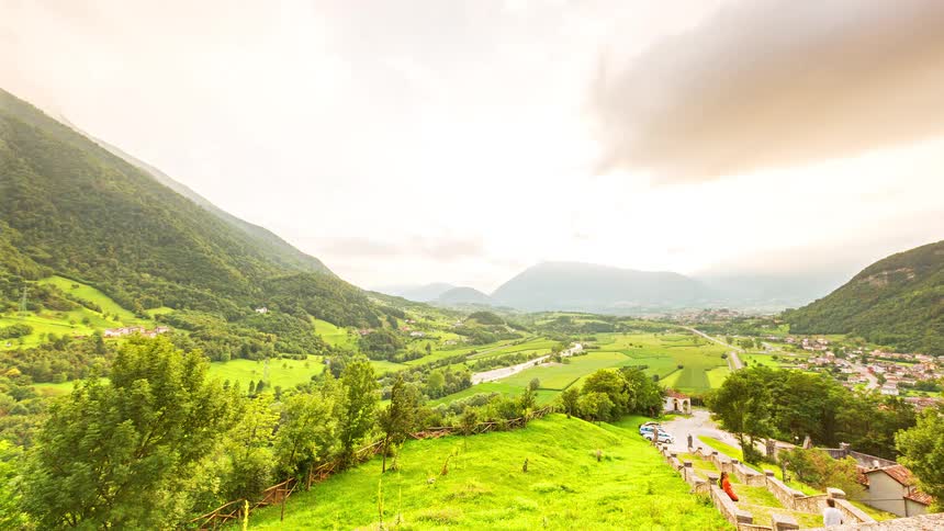 Green valley with agricultural fields between mountains under sunlight