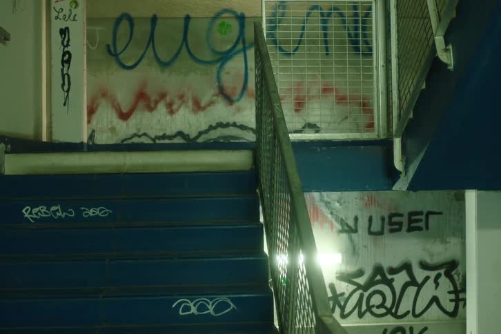An indoor stairwell is has graffiti spray painted on its concrete walls