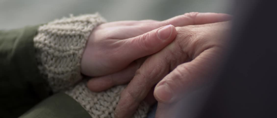 Two people sitting holding hands