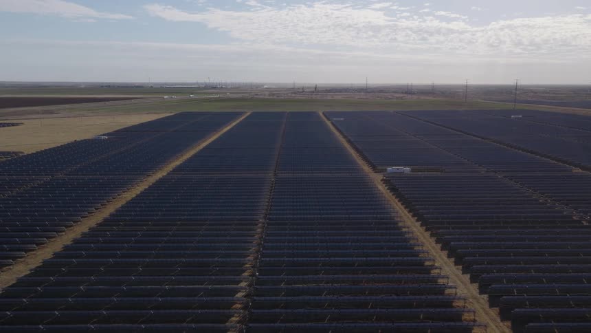 Aerial footage of a large solar farm with numerous rows of panels