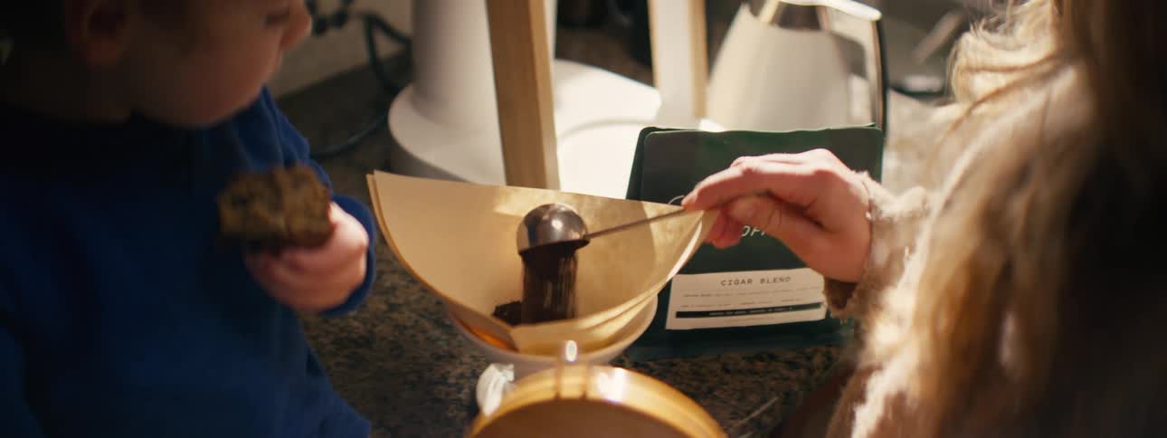 A woman making coffee next to a baby