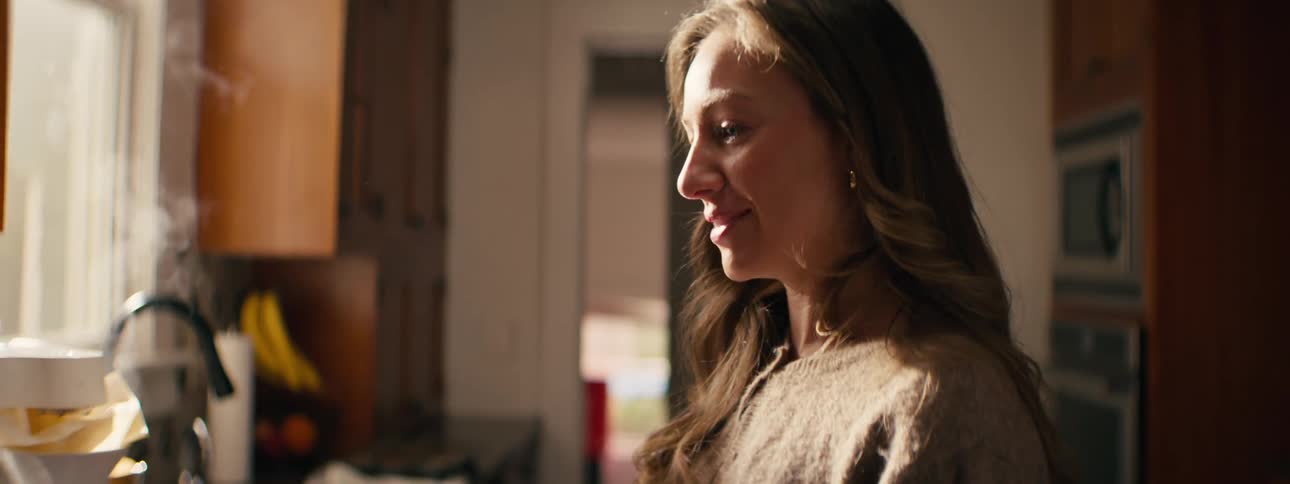 A side view shows a woman with long hair and a child smiling and talking in a kitchen during the day