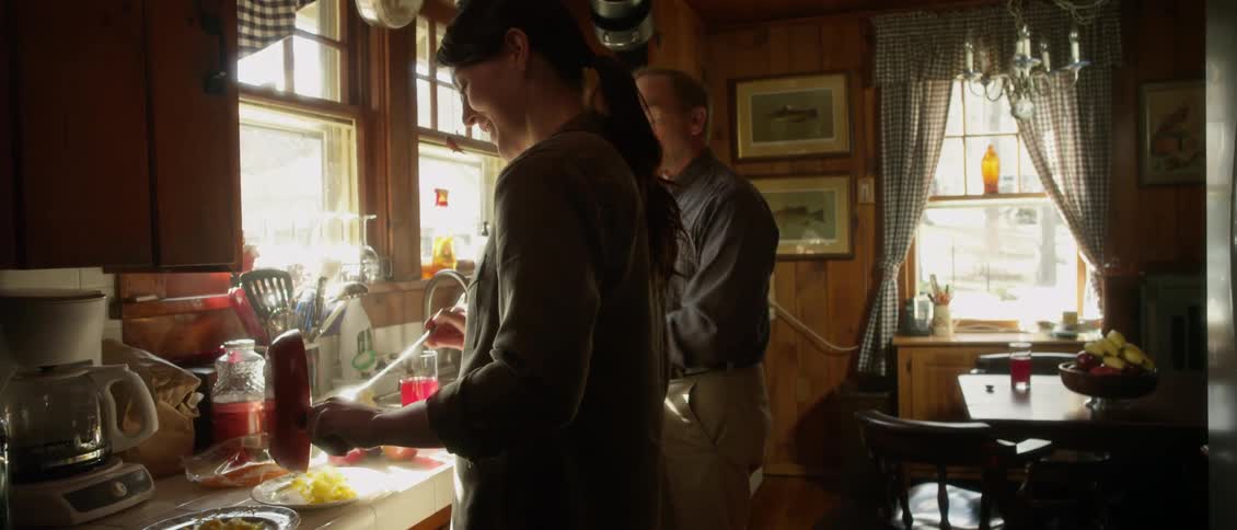 A couple laughs and talks as they work in kitchen