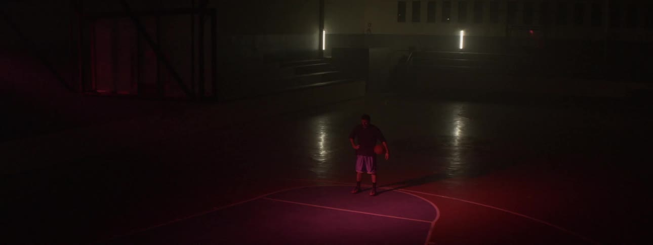 A man holding a basketball under his arm and standing on the court