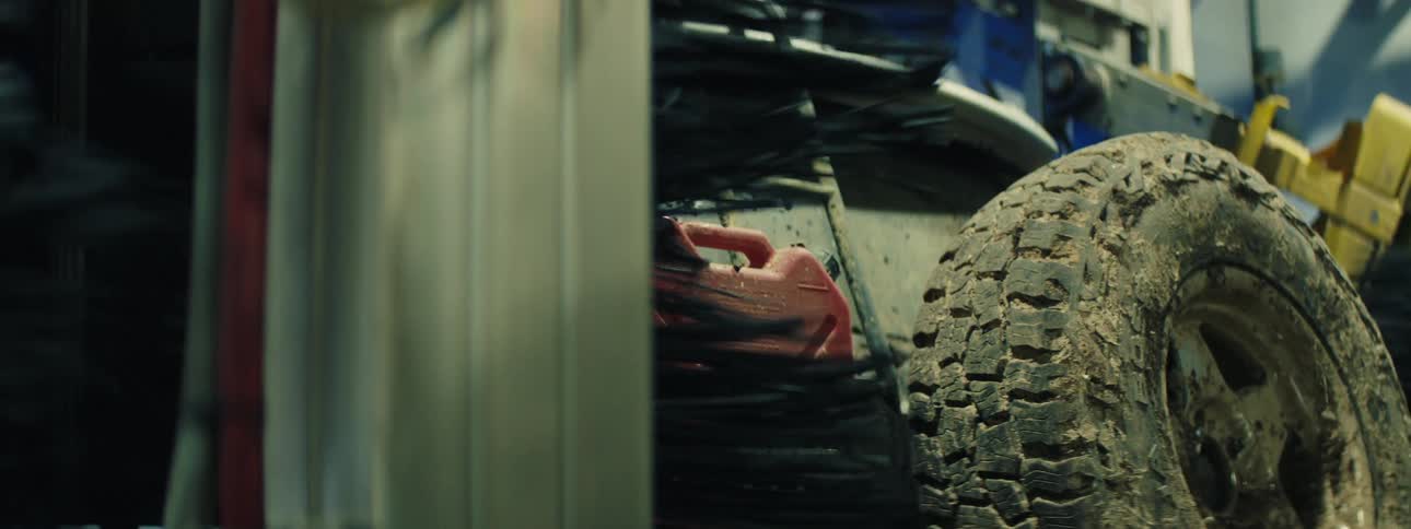 A large rotating brush cleans the rear of an off road vehicle inside an automated car wash