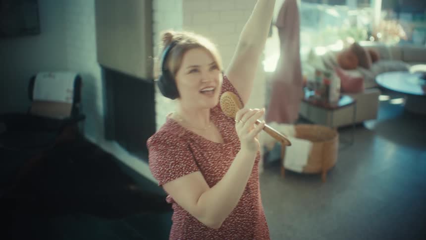 Woman singing with headphones and wooden spoon