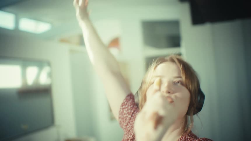 The woman is dancing and singing at home