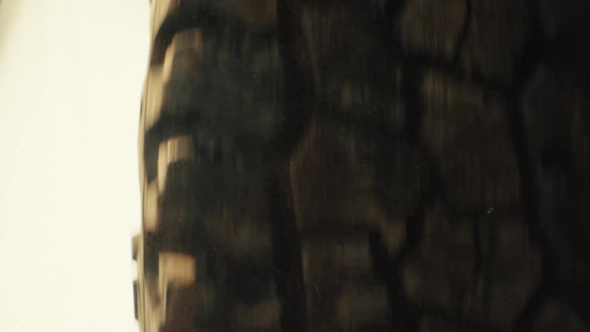 A closeup shot shows a rugged offroad tire spinning rapidly through dirt and debris the camera maintains a tight focus on the textured tread as it kicks up dust against a bright background