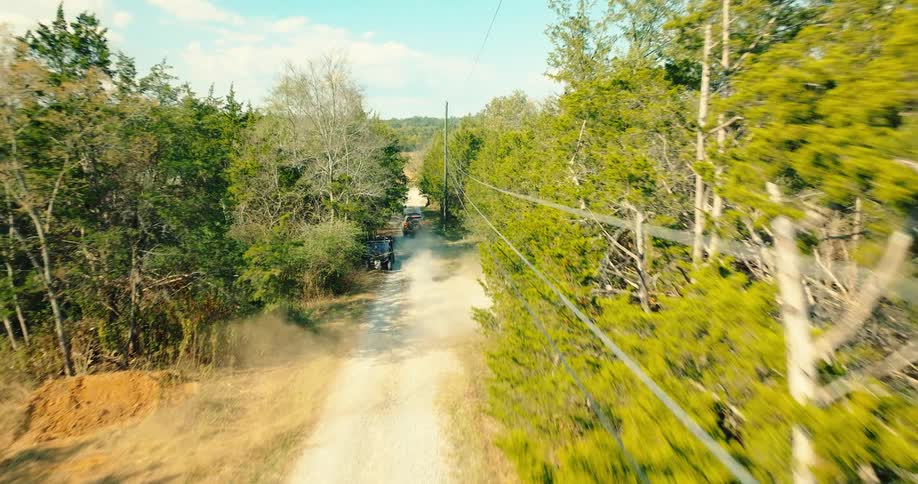 Pickup truck driving along a trail in a forest towards the highway