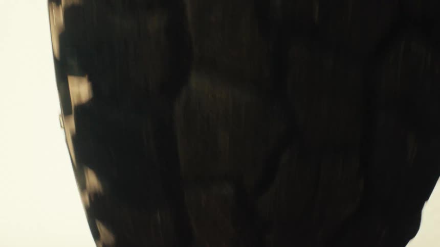 A closeup view shows a large rugged tire rolling across a dusty surface